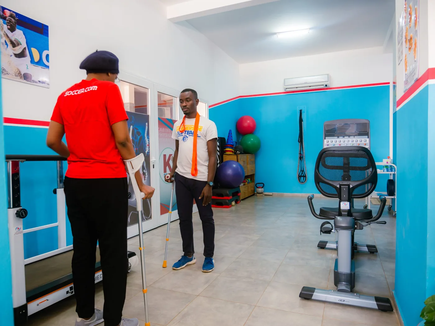 Patient en béquilles accompagné par un kinésithérapeute en salle de rééducation